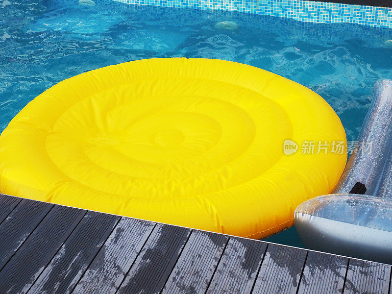 黄色的圆形充气床垫放在蓝色的池水里。夏天休息