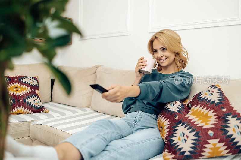 一个快乐的女人喜欢在家看电视和喝咖啡的肖像