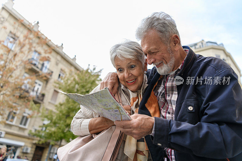 老人和他的妻子带着旅游地图在市区散步。