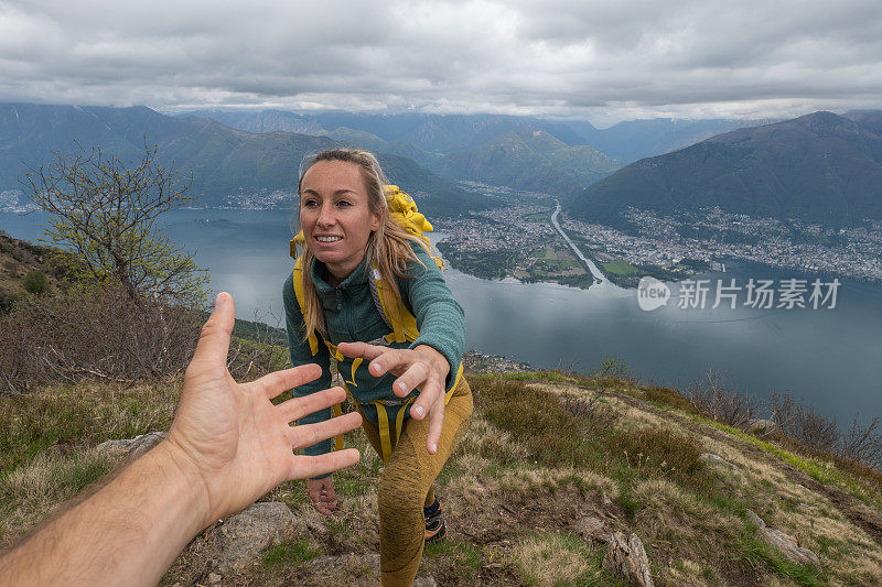 徒步旅行者帮助队友到达山顶，顶峰