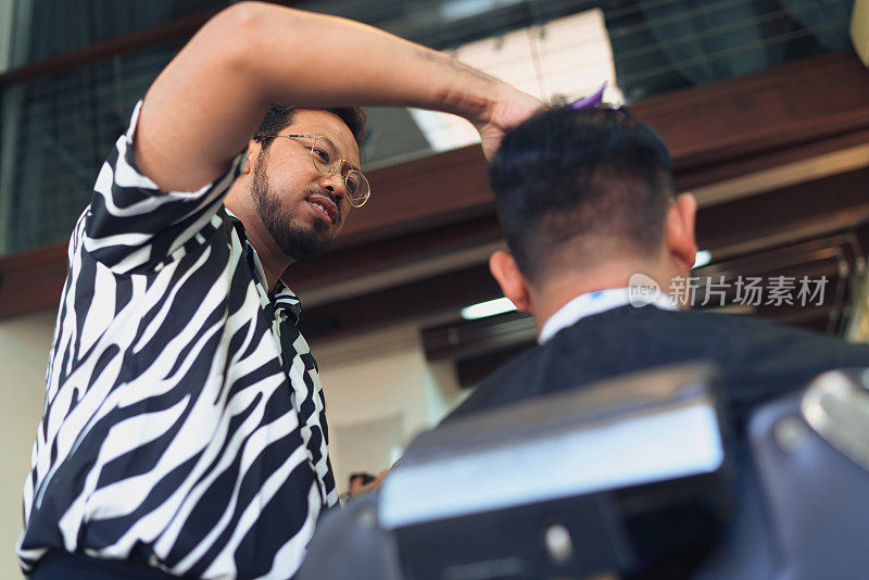理发师正在梳理亚洲顾客的头发