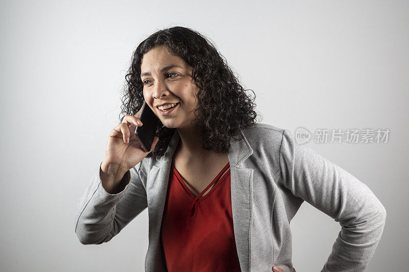 一个三十多岁的拉丁女人拿着手机在摄影棚拍照