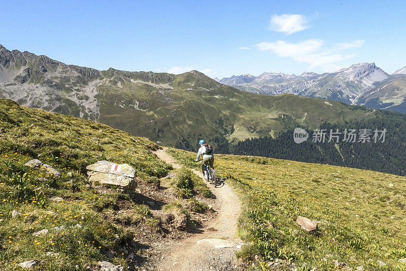 女人沿着阳光明媚的自行车道骑山地车