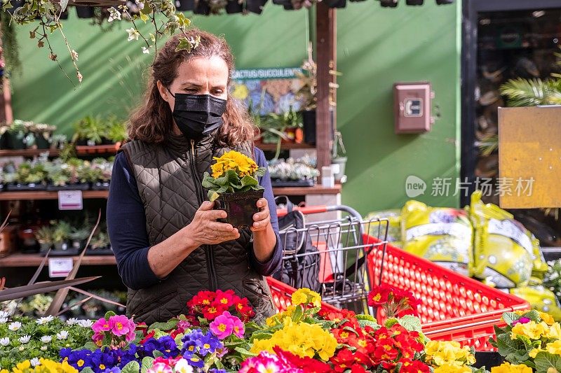 图为，戴着口罩的成熟女性在打折店的苗圃购物