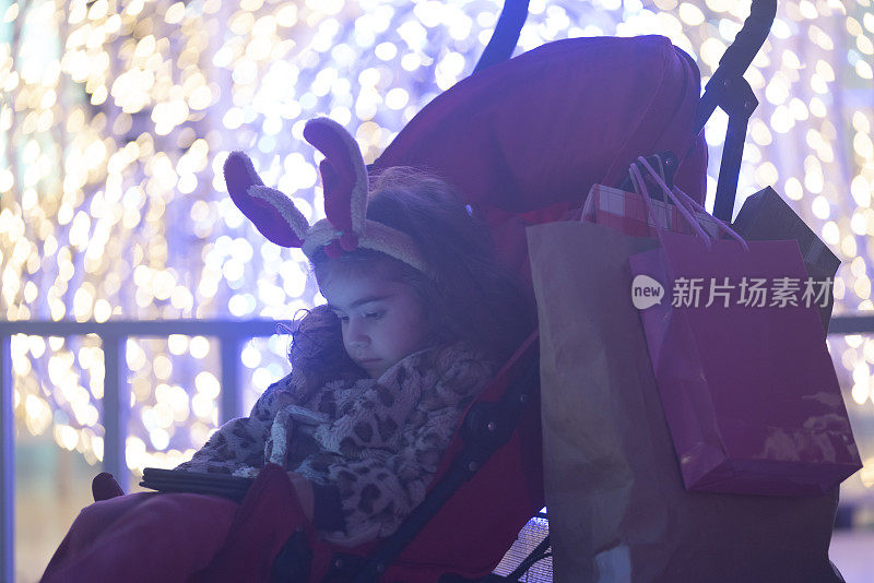 照片的女孩穿着服装驯鹿鹿角在圣诞灯前
