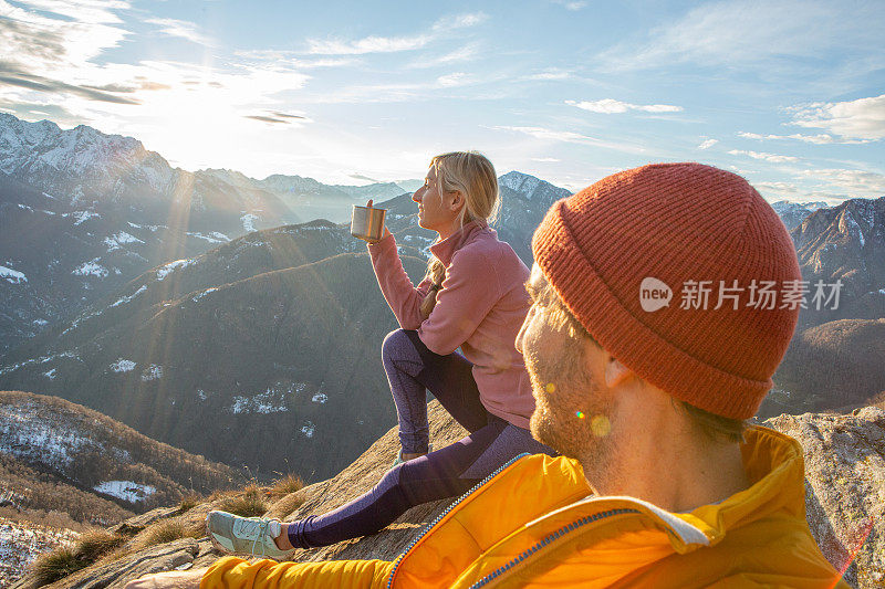 一对情侣徒步旅行，在阳光明媚的山脊上放松，享受片刻日落