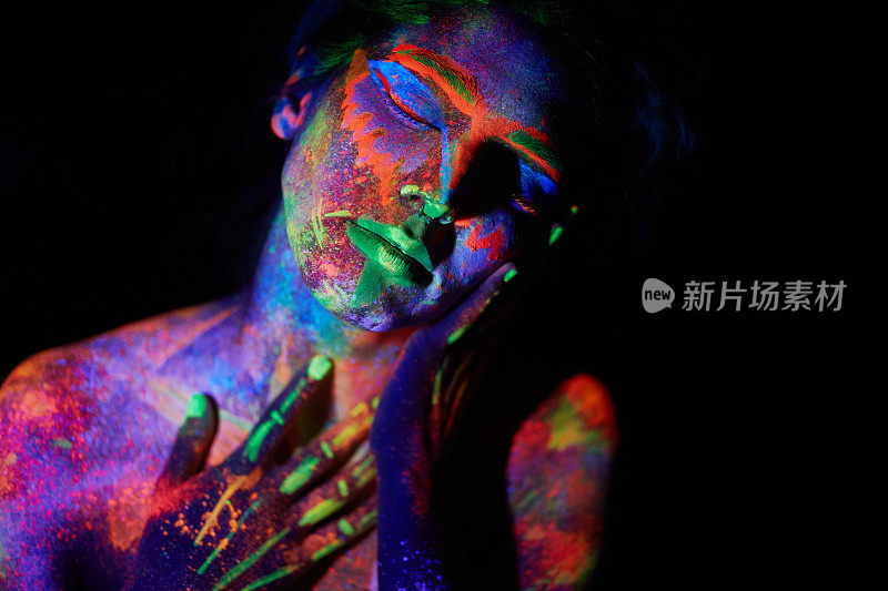 年轻女孩的肖像在紫外线灯光下霓虹灯妆在她的脸上