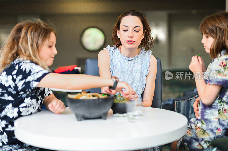 母亲和小学年龄的孩子在小咖啡馆或餐馆吃一碗薯条和鳄梨酱