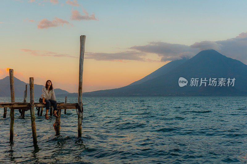 日落时分，坐在危地马拉阿提特兰湖码头上的女人