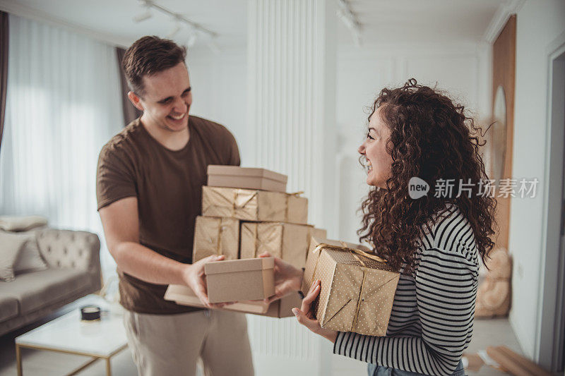 年轻的男女夫妇在他们的家里，互相赠送礼物，享受一个美丽的情人节或某人的生日