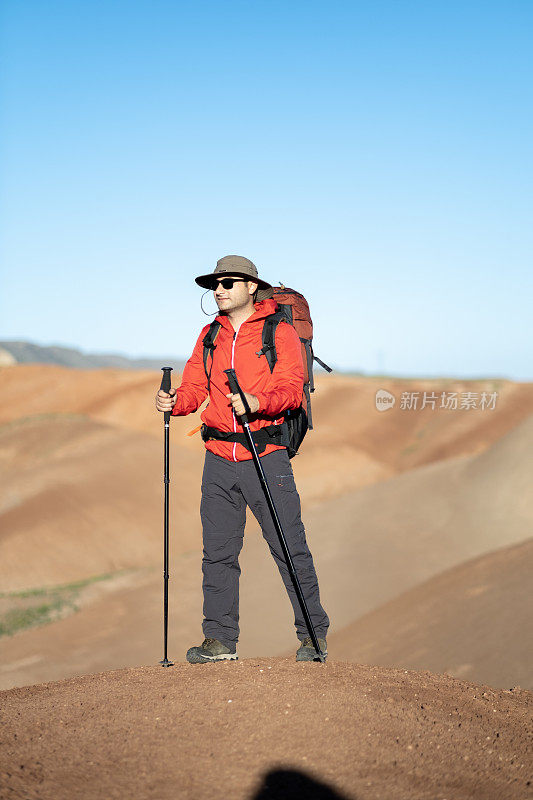 日落时分，一个男人站在春山的悬崖上欣赏大自然的景色