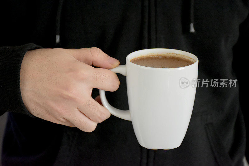 喝咖啡时，一名男性手捧一杯咖啡