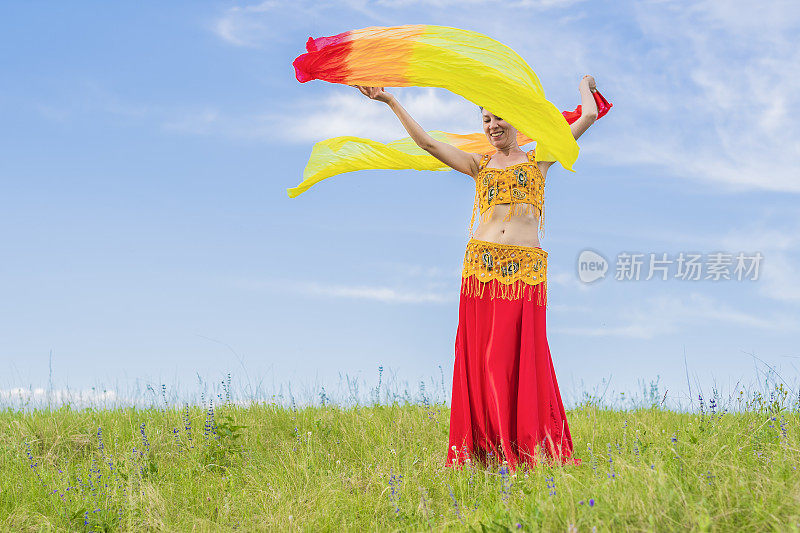 身着民族服装的年轻女子在大自然的膝上跳着东方舞蹈