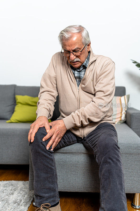 一位老人坐在家里，感到膝盖慢性疼痛，难以忍受。