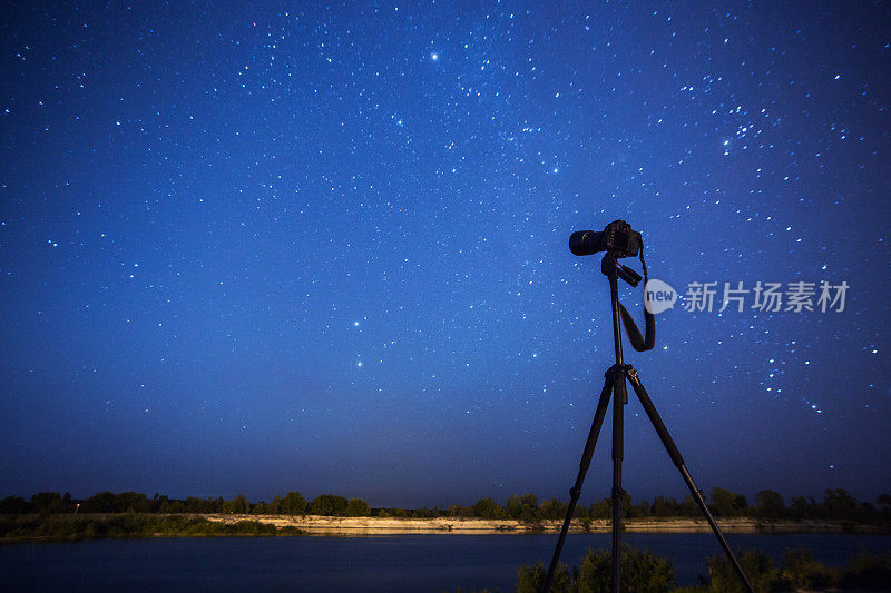 摄影相机在三脚架上的背景上的夜空星空。星星。景观