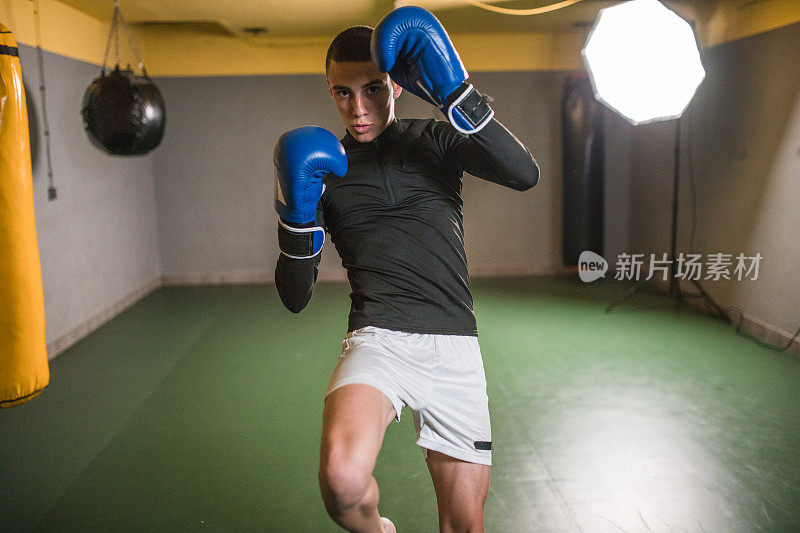 戴着拳击手套的强壮的男拳击手正在拳击馆里训练，为一场拳击比赛和拳击比赛做准备