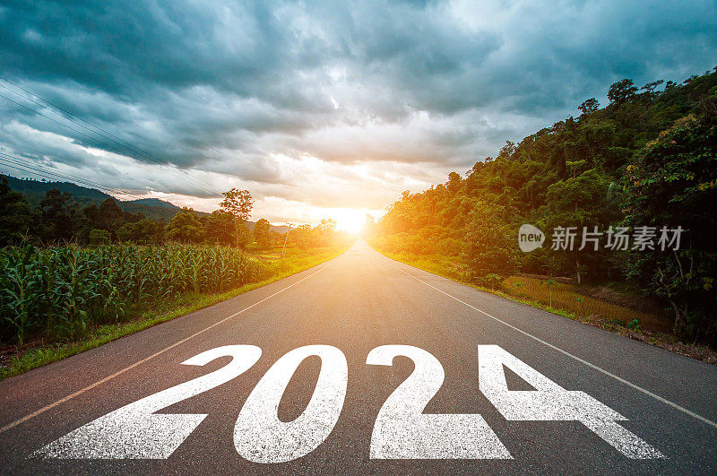 2024年新年概念。文字2024写在马路中间的柏油路与日落。计划的概念，目标，挑战，新年决心。