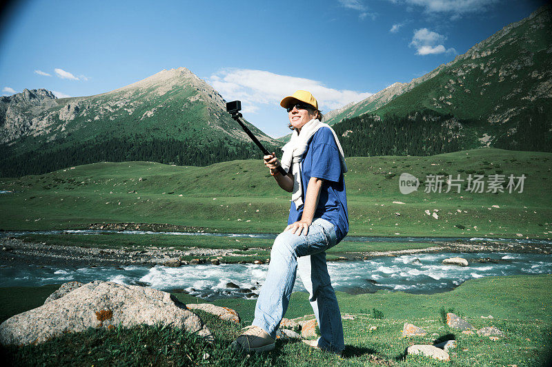 一位背包客正在拍摄她在山河上的旅行视频