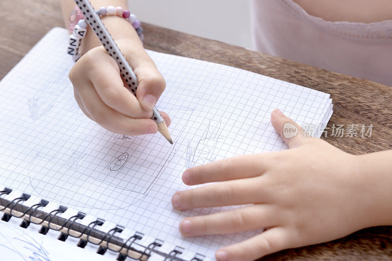 4岁学龄前女孩在格子笔记本上用笔画元素，教育过程，手部护理理念，儿童教育，灵巧性和协调性的发展