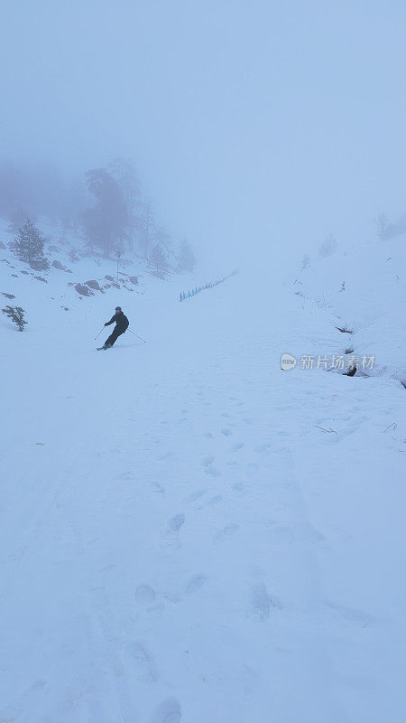 滑雪者从山上雕刻的冬季滑雪斜坡上滚下来