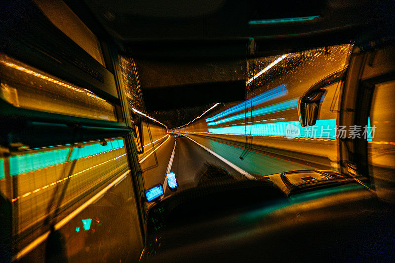 在高速公路隧道中行驶的大巴司机座位上的绿色隧道灯