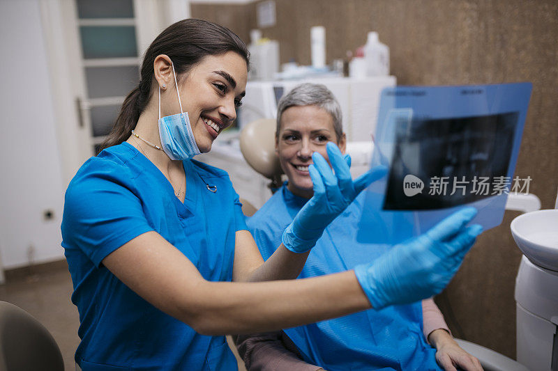 阳性的女牙科医生在医院与病人分享牙齿x光图像