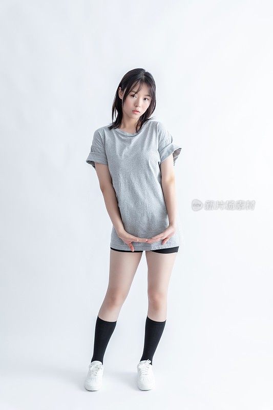 一名身穿灰色t恤和黑色短裤的年轻亚洲女子双手交叉在胸前摆姿势。