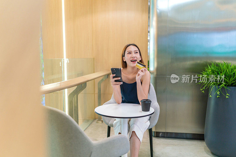 年轻的亚洲女性在咖啡厅用智能手机进行数字银行信用卡交易