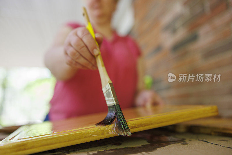 刷菜板。不认识的女人用矿物油保护木制砧板。表面水平，专注于画笔