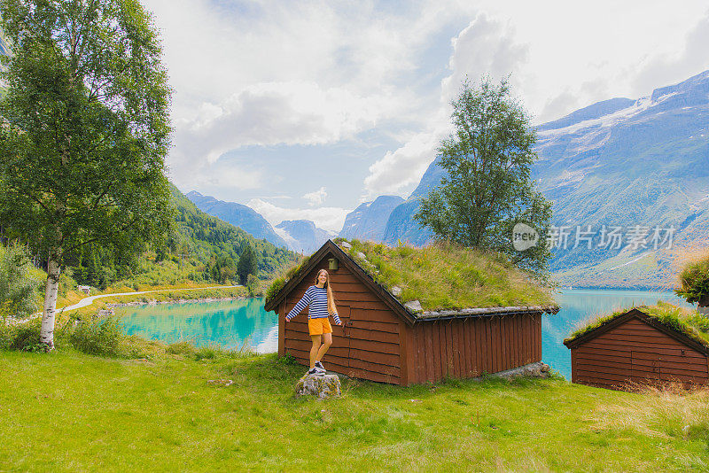 快乐的女游客在挪威的山村漫步，欣赏美丽的湖景