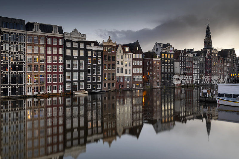 观光船和运河房屋在Damrak在阿姆斯特丹市中心