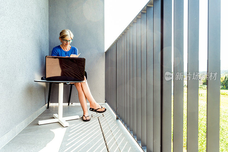 自由女性在酒店阳台上用笔记本电脑工作