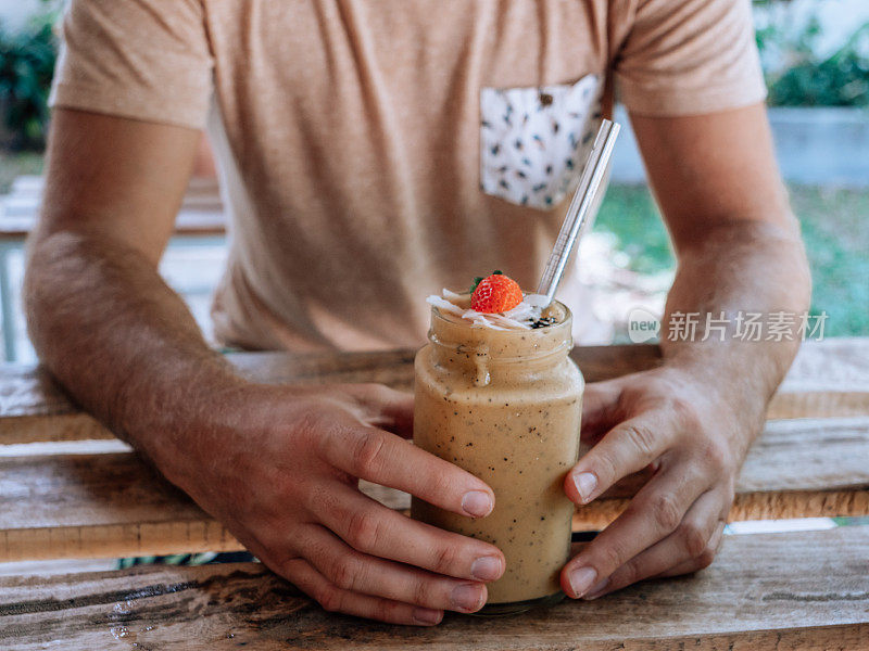 一个男人在咖啡馆喝着新鲜的冰沙