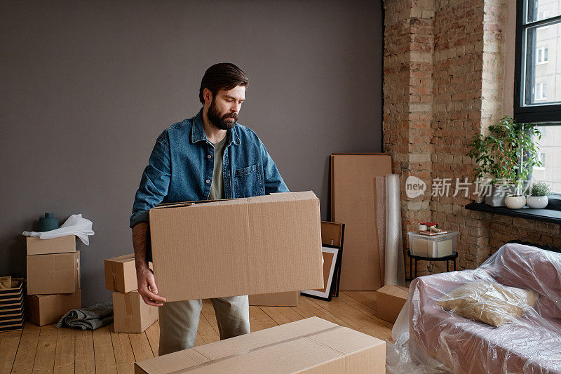 一个年轻人搬着装满东西的箱子搬到新公寓的水平镜头