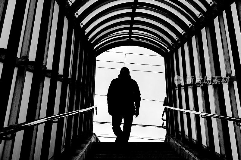 一个爬楼梯的男人的背影剪影，黑白