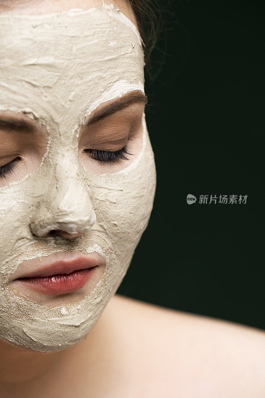 美丽的年轻加码的妇女与化妆品面膜作为她的皮肤护理常规的一部分