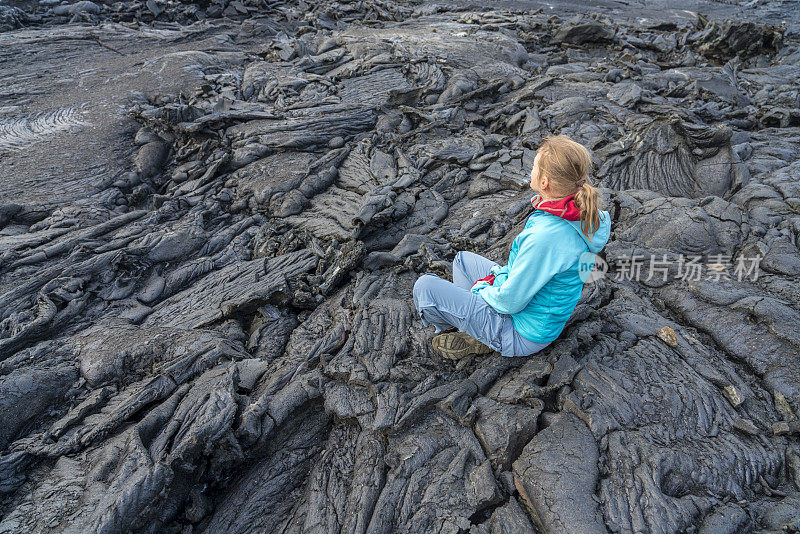 女人们坐在Fagradalsfjall火山冷却的黑色熔岩上