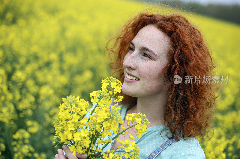 一个年轻的女人在油籽地里