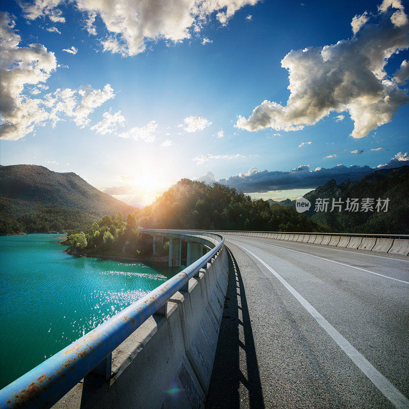 在夕阳西下的西班牙山间，一座横跨翡翠湖的桥