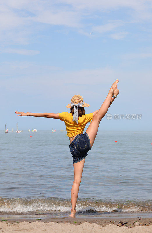 身材苗条的女孩一边做体操，一边带着帽子到海边