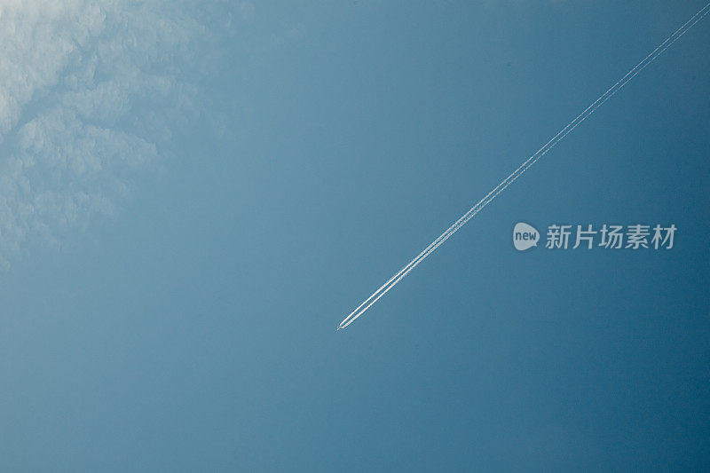 蓝色天空中带着水汽尾迹的飞机的低角度视图