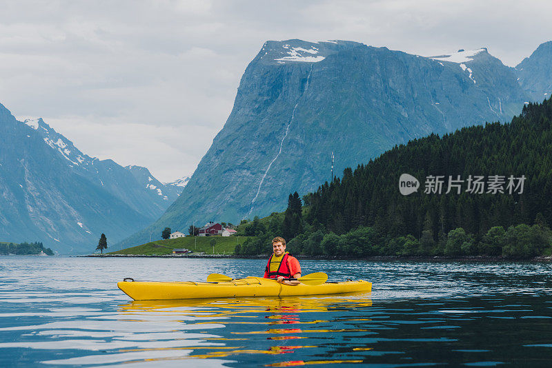 在挪威的峡湾上享受夏天皮划艇的一个男人的侧面视图