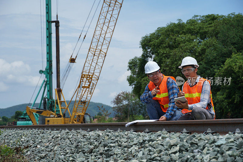 2名亚洲工程师在外面检查修建一条高速铁路。