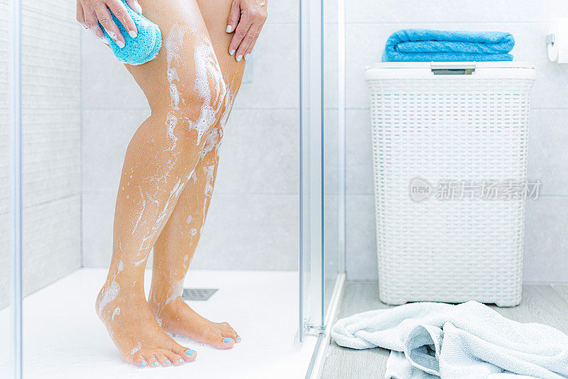 一个女人在淋浴间用海绵擦洗她的腿