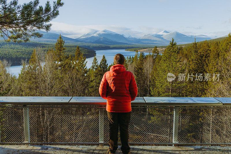 一名身穿红色夹克的男子在挪威隆丹国家公园风景优美的山景视点上行走的后视图