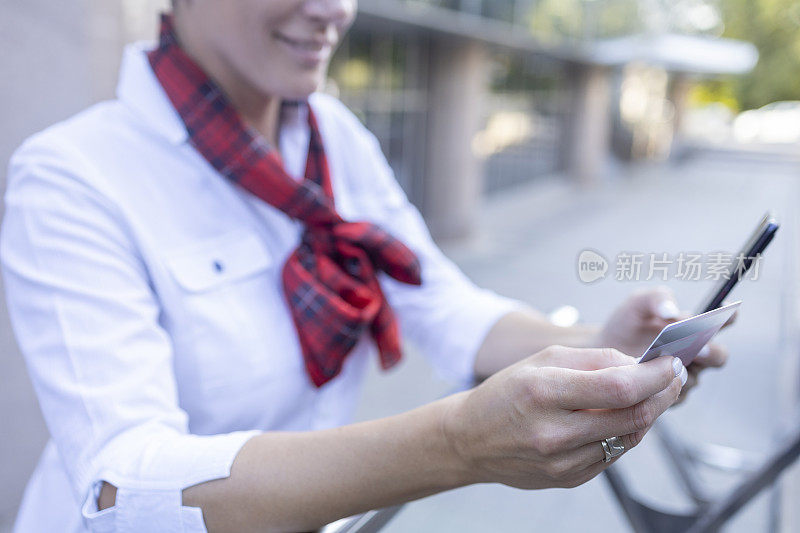 女性手持智能手机和信用卡的特写镜头