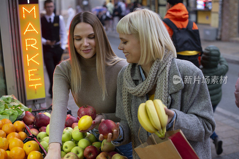 年轻快乐的妇女购物蔬菜和水果的市场库存照片