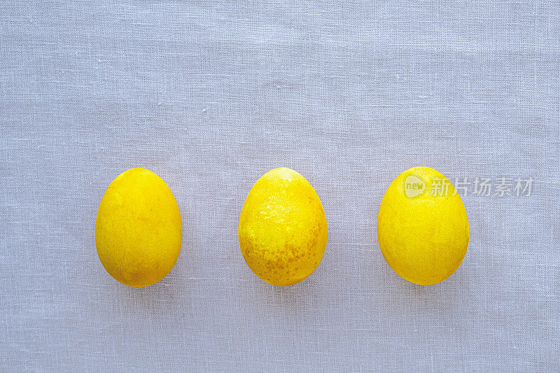 自然染色的黄色鸡蛋在中性背景，俯视图，平lay。复活节快乐。文本复制空间。