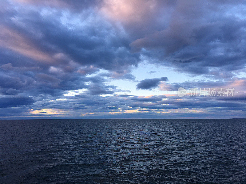 一天结束时，冰岛Húsavìk的海洋上有彩色的云