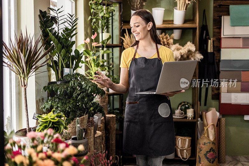 花店里卖花的人正在摆弄笔记本电脑